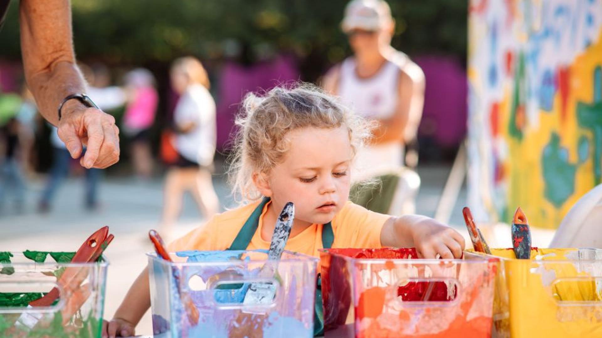 Child plays with paint at a local art event.