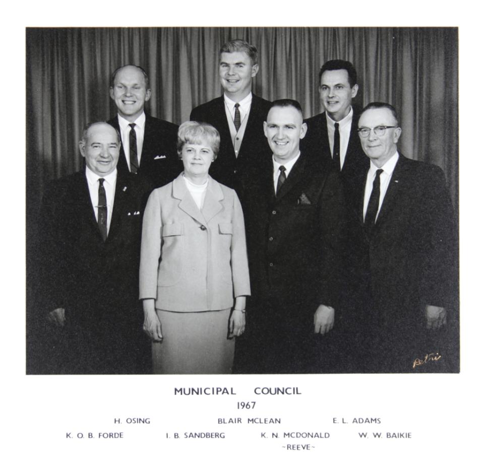 Black and white group portrait of seven people in formal attire, 1967.