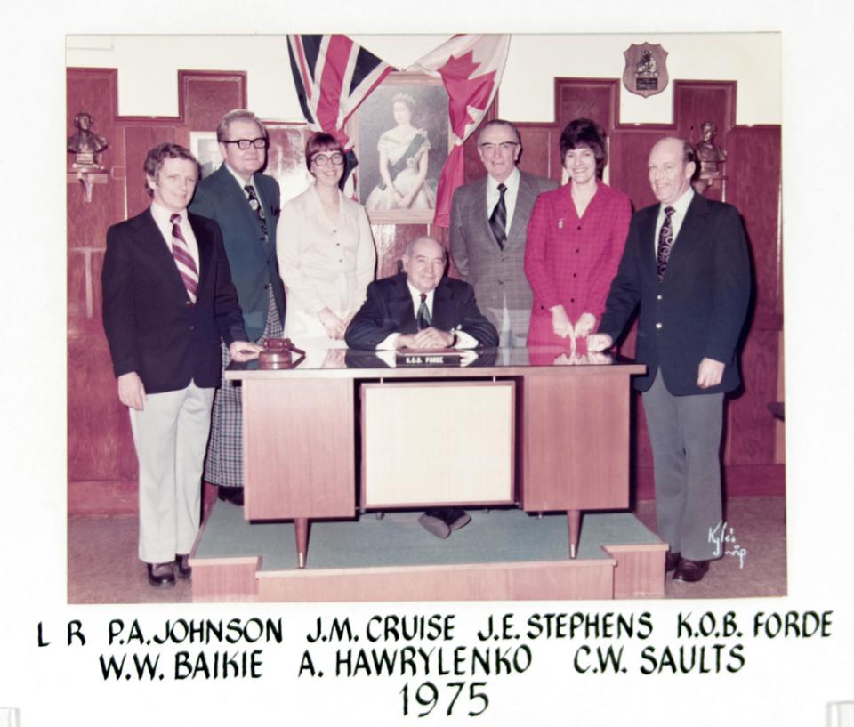A group of men and women pose around a desk, old photograph from 1975.
