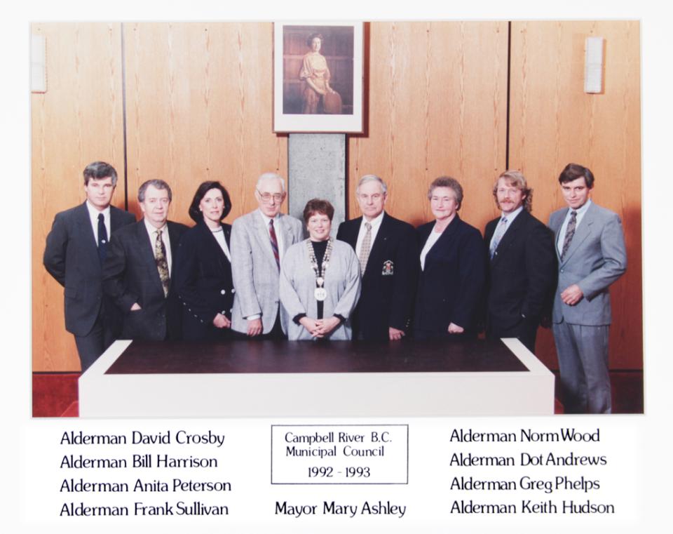 Nine people stand in formal attire, posing in an office setting.