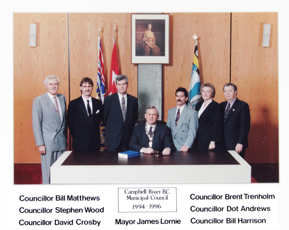Group photo of eight people in formal attire in an office setting.