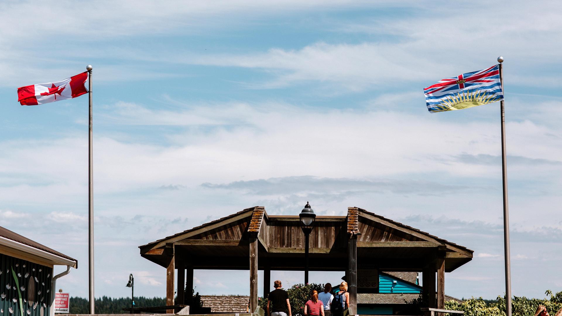 People walking up stairs to the Pier entrance in between the Canadian and British Columbia Flag.