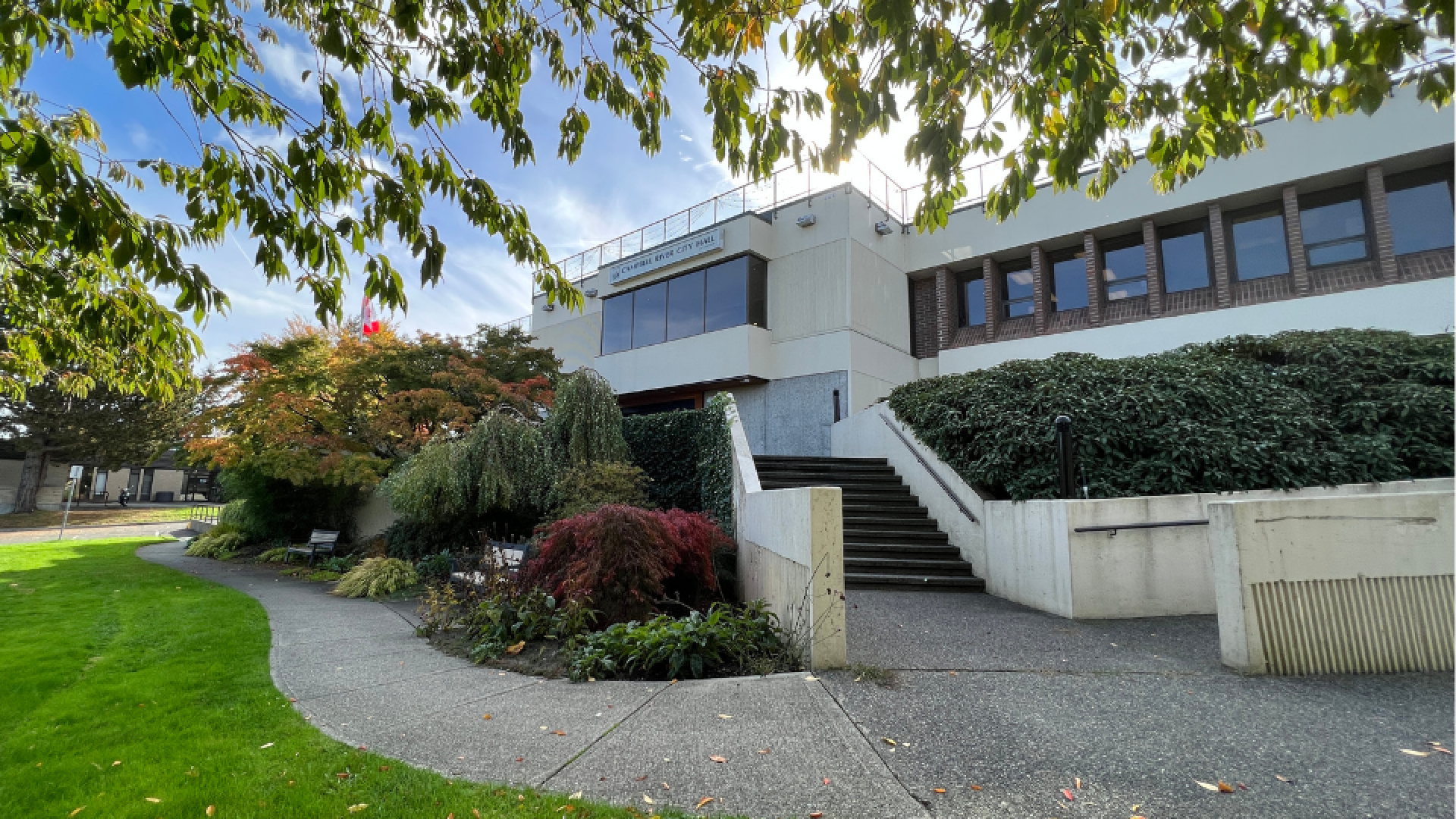 Front entrance of City Hall with stairs leading to front door, surrounded by landscaping and a walkway.