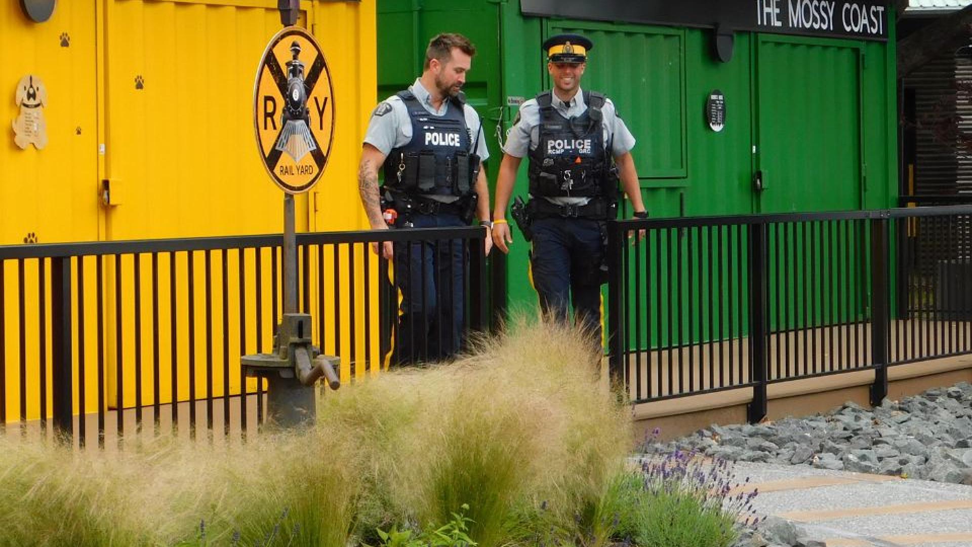 Two police officers smiling and patrolling the streets in front of the Rail Yard Market.