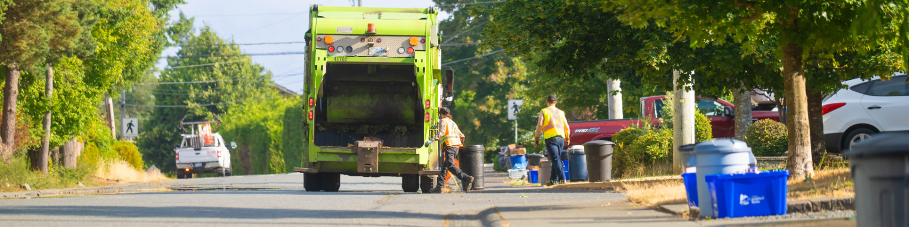 Two workers collect garbage and recycling for garbage truck