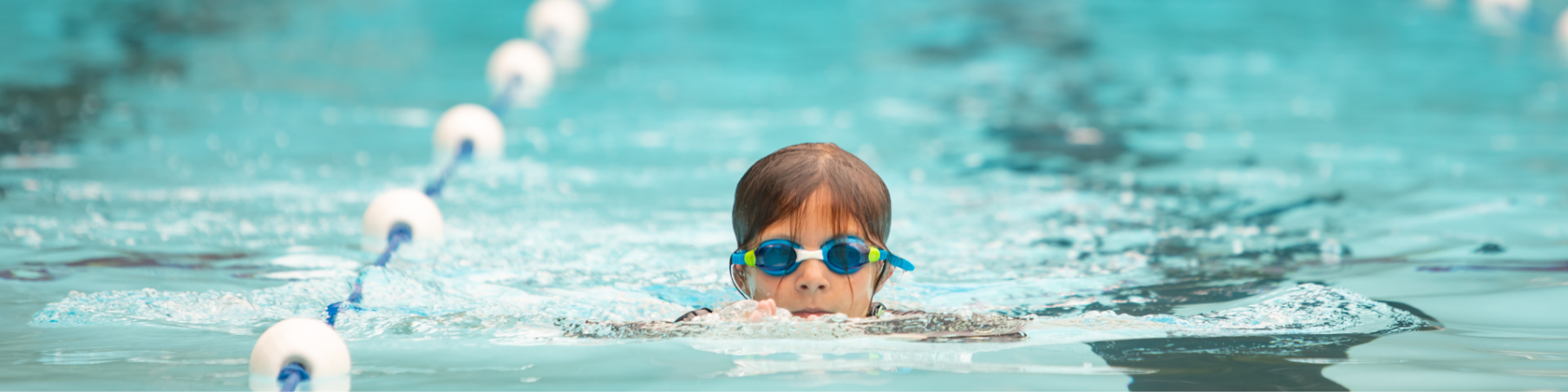 Child doing laps in a pool wearing goggles