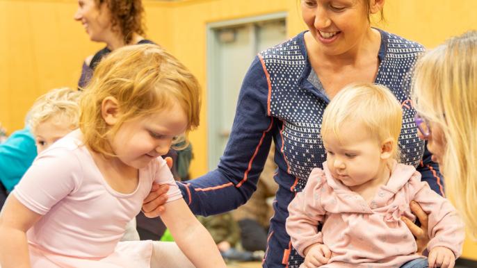 Two children playing indoors at the Community Centre with smiling adults, engaging in fun activities to celebrate National Child Day.