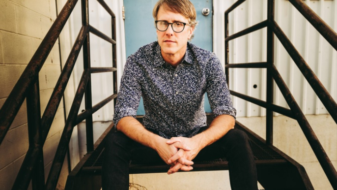 Jeremy Facknitz sitting on a staircase with crossed hands looking at the camera.